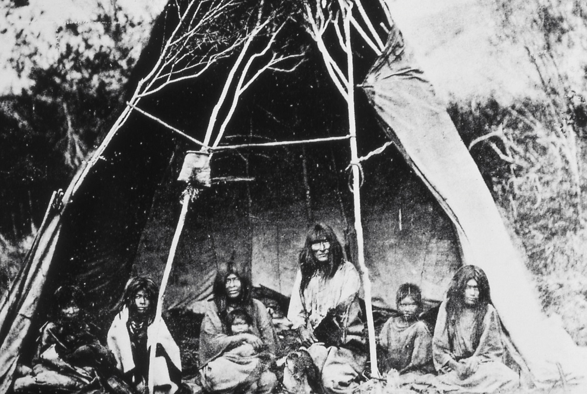 Black-and-white photo of Indigenous people in a dwelling or teepee