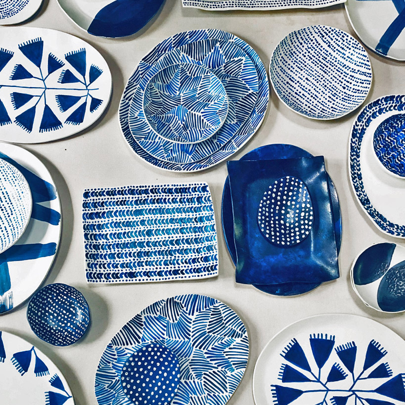 Examples of Michele Michael's ceramics, these featuring freehand painting with indigo and cobalt underglazes A variety of ceramic plates, bowls, and platters, all featuring white and blue painted patterns
