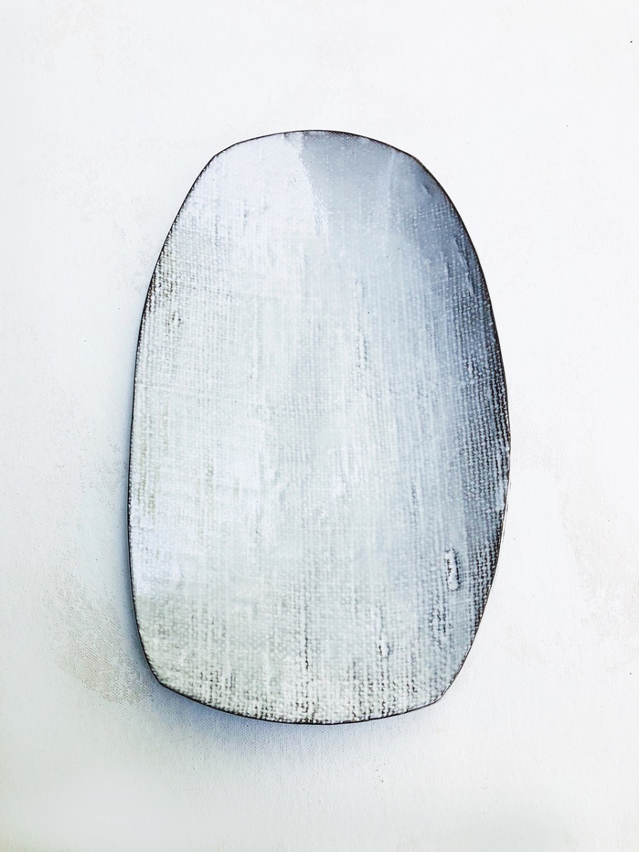 One of Michele Michael's ceramic platters, with texture created by rolling out the clay between two pieces of handwoven linen White rectangular platter with rounded corners with slightly visible dark mesh pattern underneath