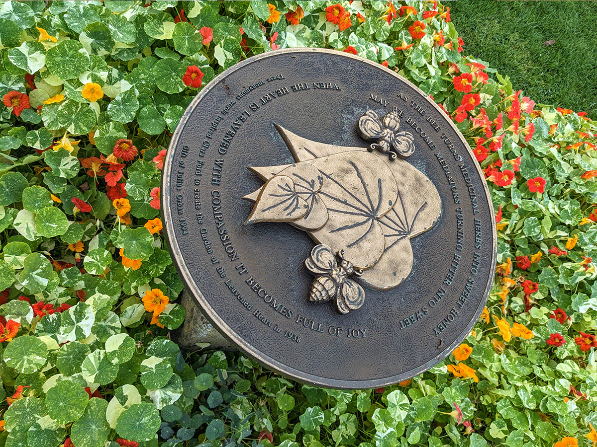 The plaque reads: “As the bee turns medicinal herbs into sweet honey