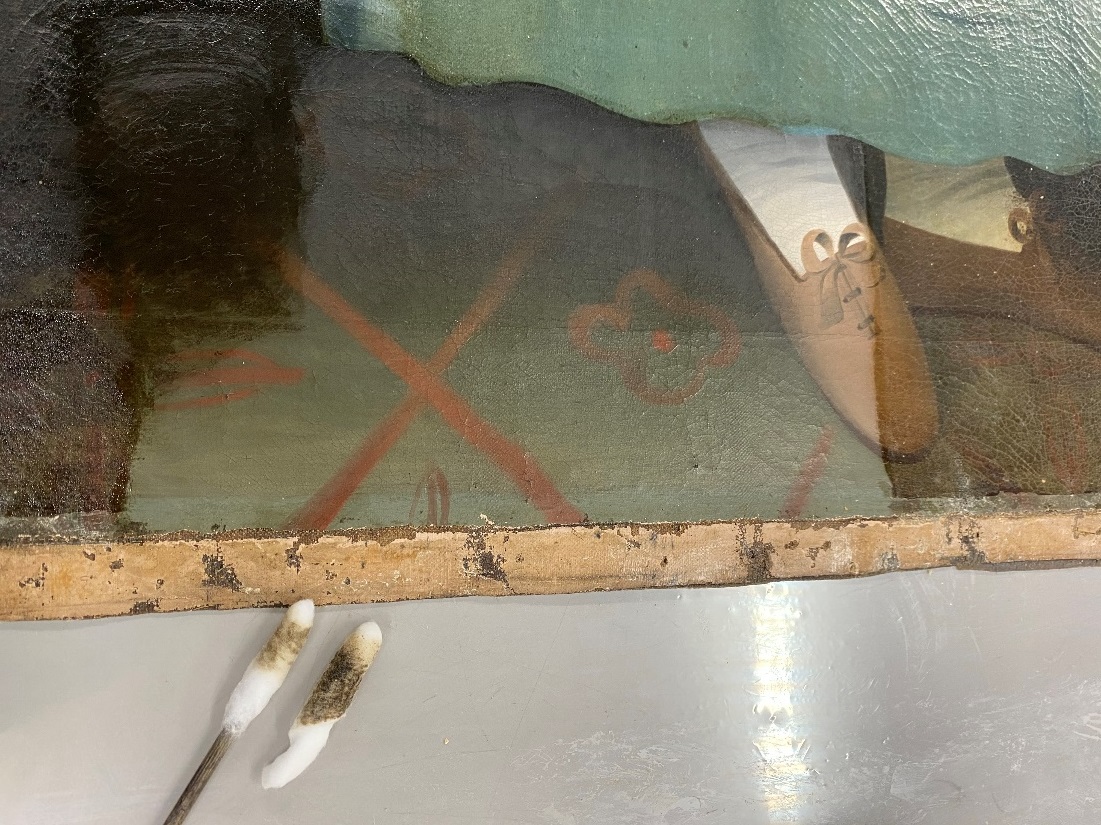 Detail shot of varnish and dirt removal from the floor Bottom of painting canvas showing floor and shoes, with one portion lighter than the remainder; tools nearby