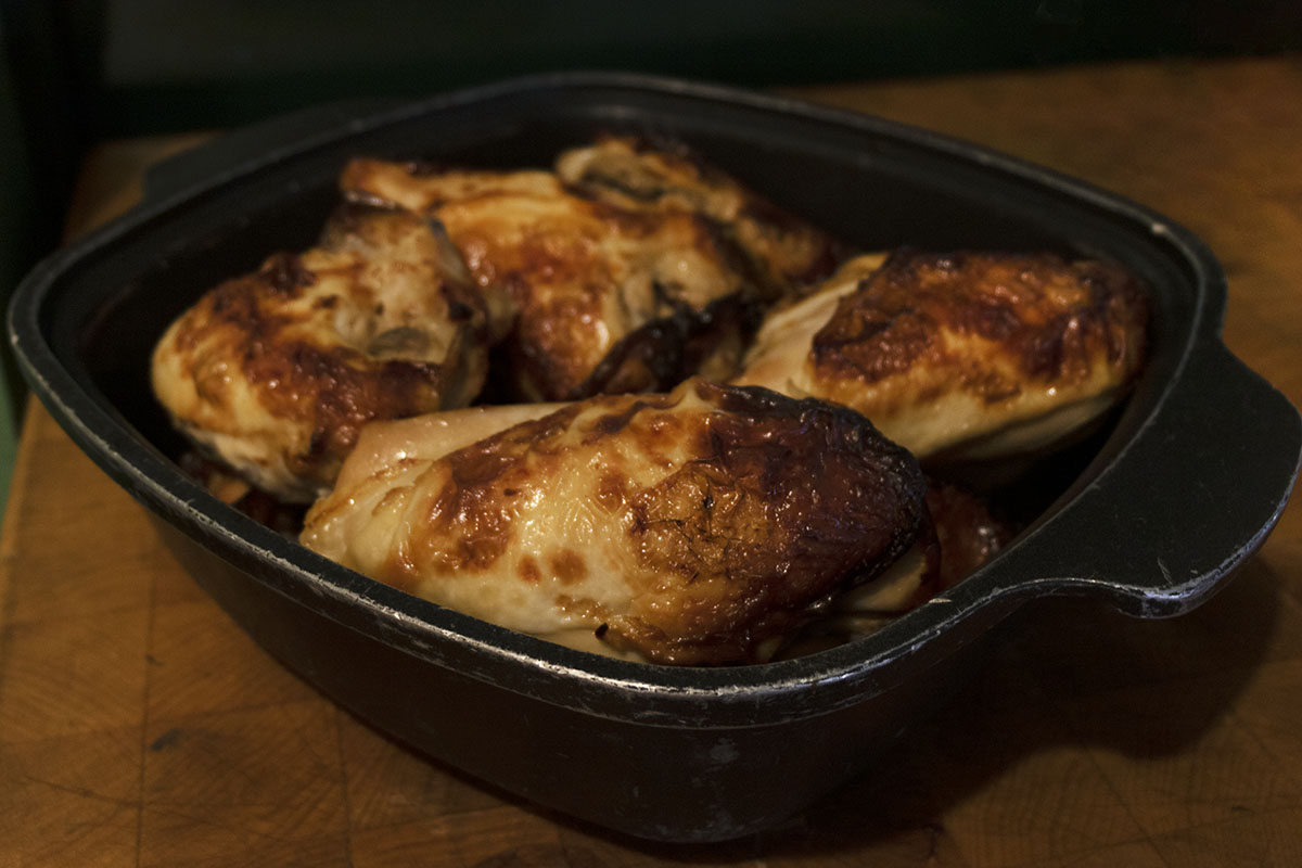 Four roasted chicken breasts in a cast iron dish on a butcher's block