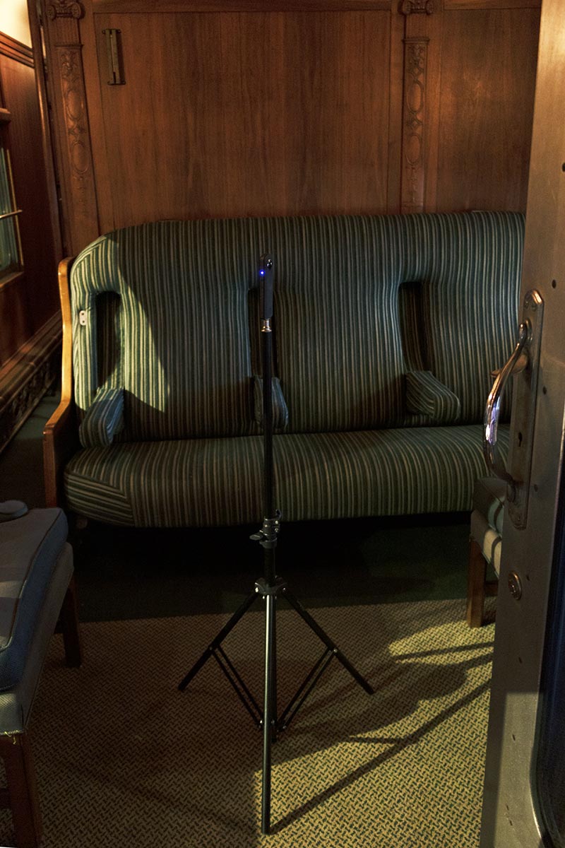 Small camera on a tripod in a room in front of striped upholstered seating