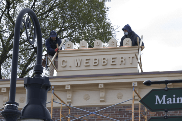 GIF cycling through several images of people working with a sign on a rooftop