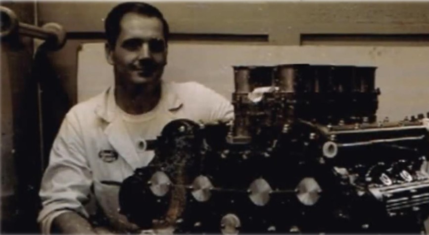 Mose Nowland with an engine Black-and-white photo of man with a car engine