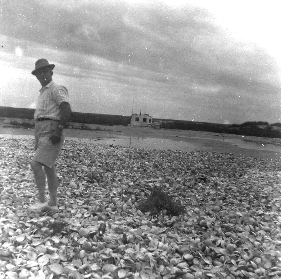James Croxton, great-grandfather of Travis and Ryan Croxton Black-and-white photo of a man wearing shorts, a short-sleeved button down shirt, and a hat walks across a beach made of oyster shells