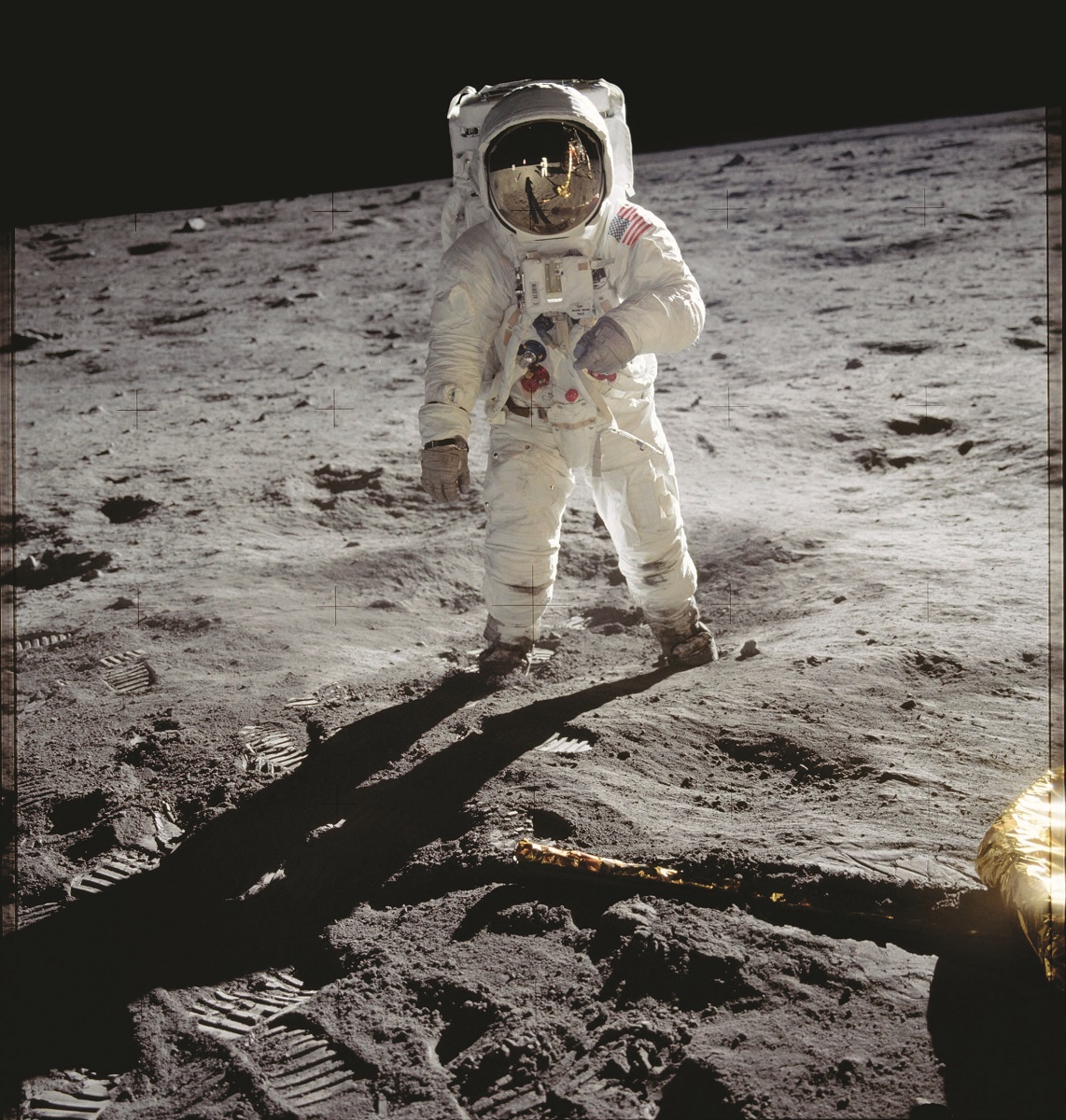 Person in spacesuit stands on the lunar surface with black space behind them