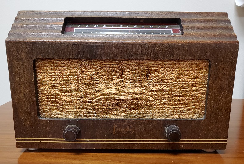 Rectangular brown radio with two knobs and tan-colored fabric on front