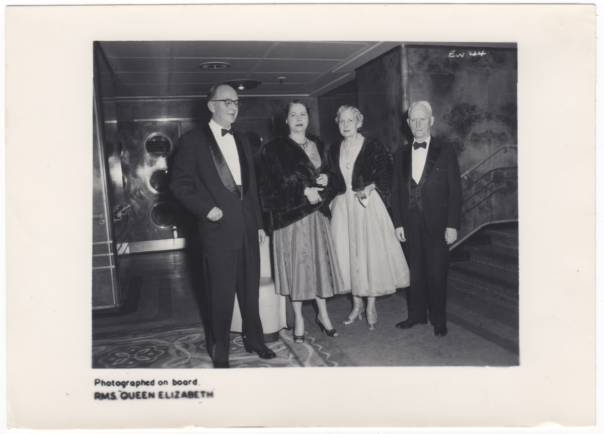 Black-and-white photo of two men in tuxedos and two women in evening gowns and short fur jackets