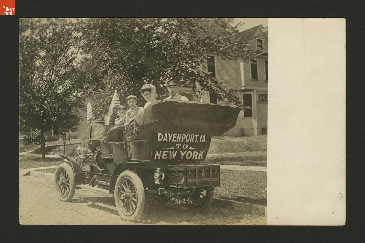People sitting in an old-fashioned open car, with 