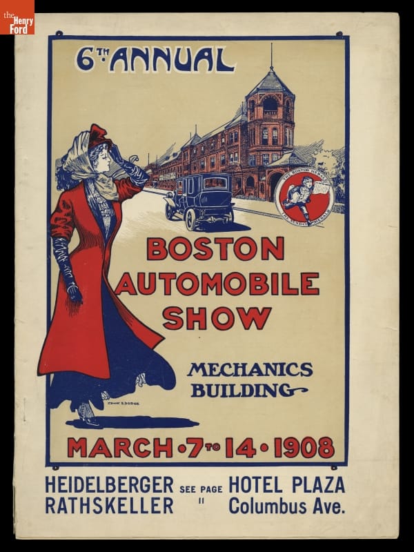 Woman in red coat and hat with scarf tied under chin as car drives down road with red brick buildings nearby
