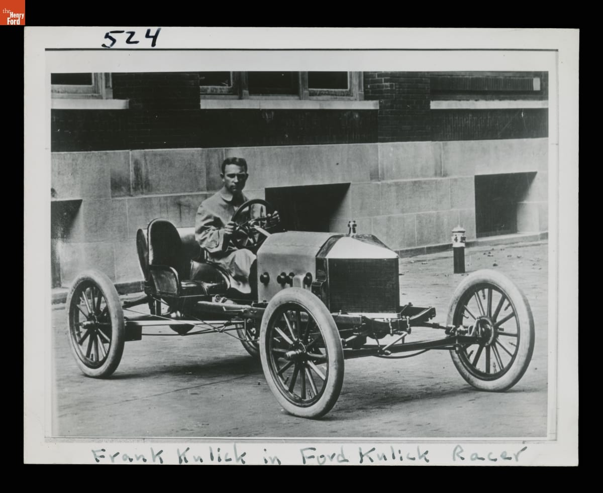 Frank Kulick Sitting in the 1910 Ford Model T Race Car Black-and-white photo of man sitting in early open race car in front of building
