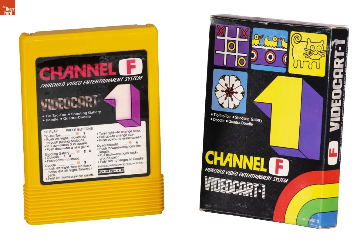 Boxy yellow game cartridge with graphic label containing text, next to black box with graphics and text