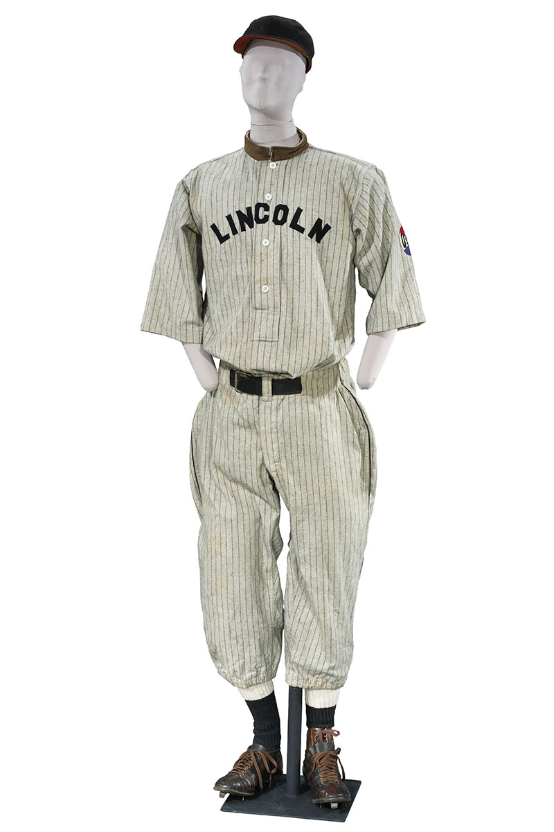 Mannequin wearing striped baseball uniform (shirt, pants, stockings, cleats, and cap)