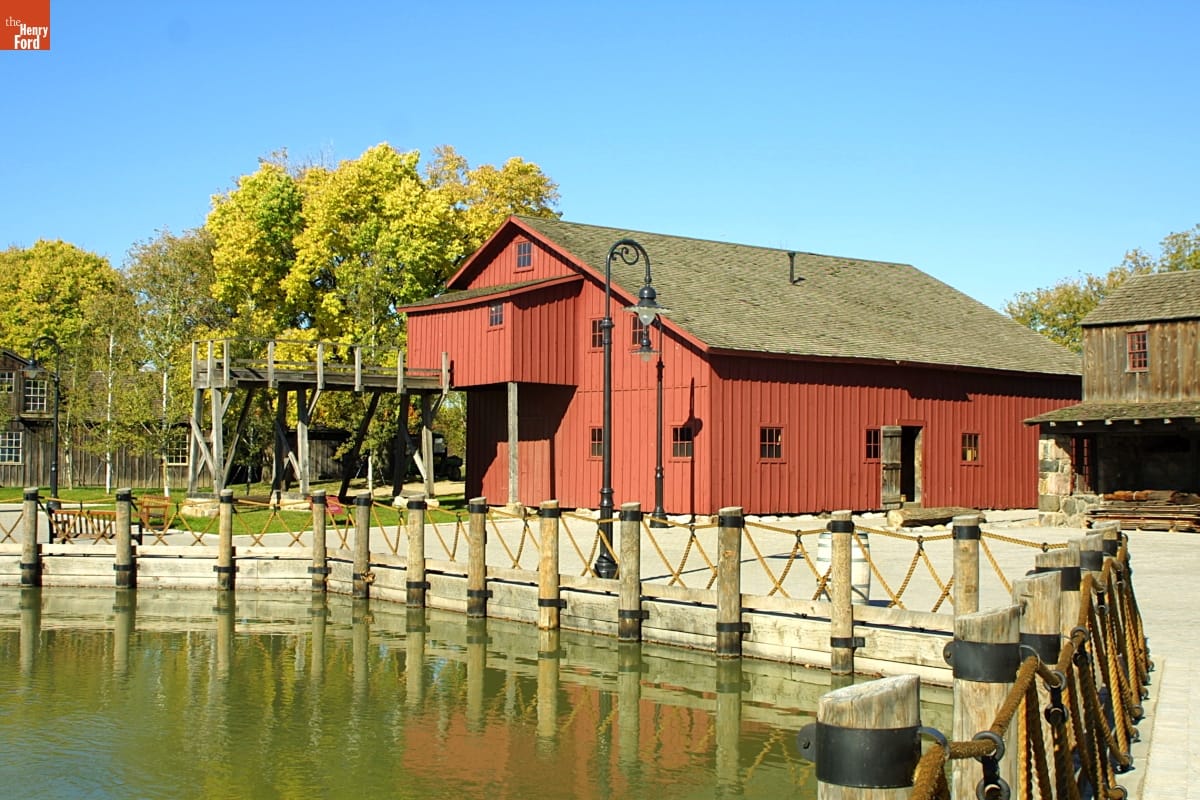 Tripp Sawmill Red wooden building among other buildings by a pond