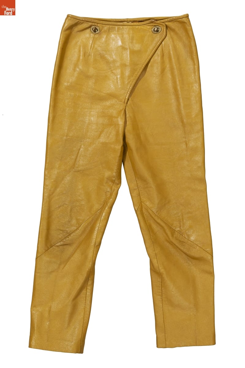 Mustard-colored leather pants with triangular flap at fly buttoning at two places at the waist