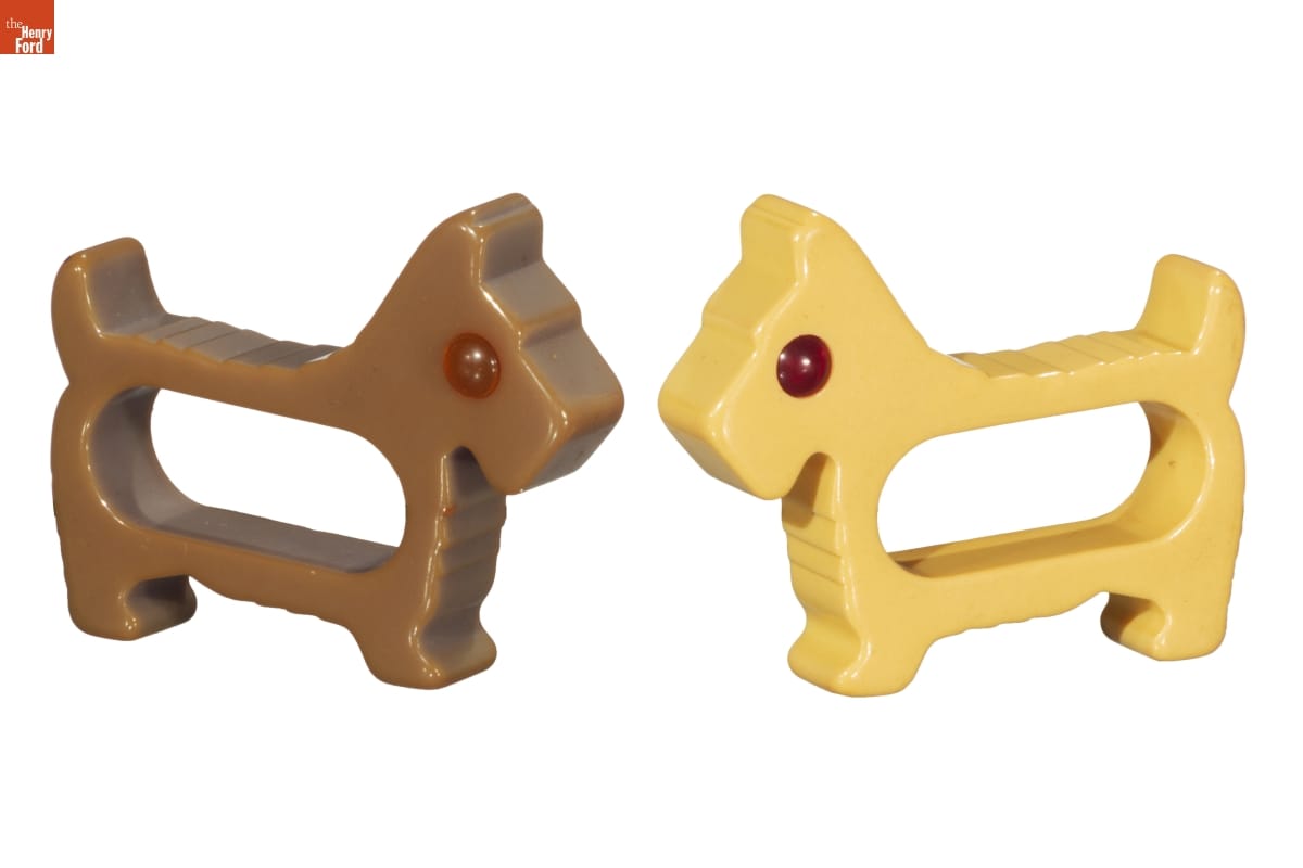 'Scottie' (Scottish Terrier) Napkin Rings, 1930-1950 Two napkin rings, one beige and one brown, in the shape of Scottie dogs with red eyes
