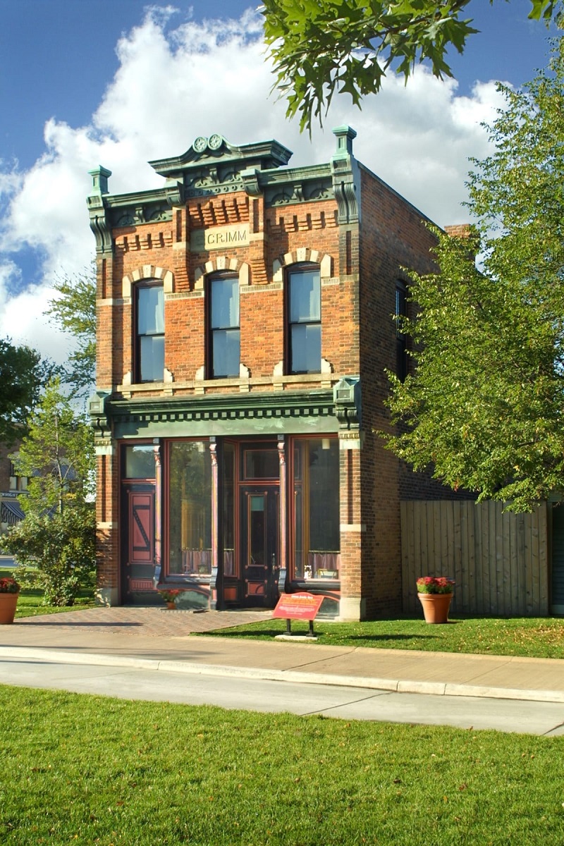 Narrow, two-story red brick building with decorative windows and cornice
