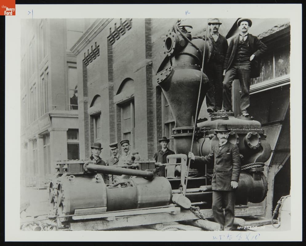 Henry Ford with Other Employees at Edison Illuminating Company Plant, November 1895 Black-and-white photograph of men standing among machinery outside a large brick building