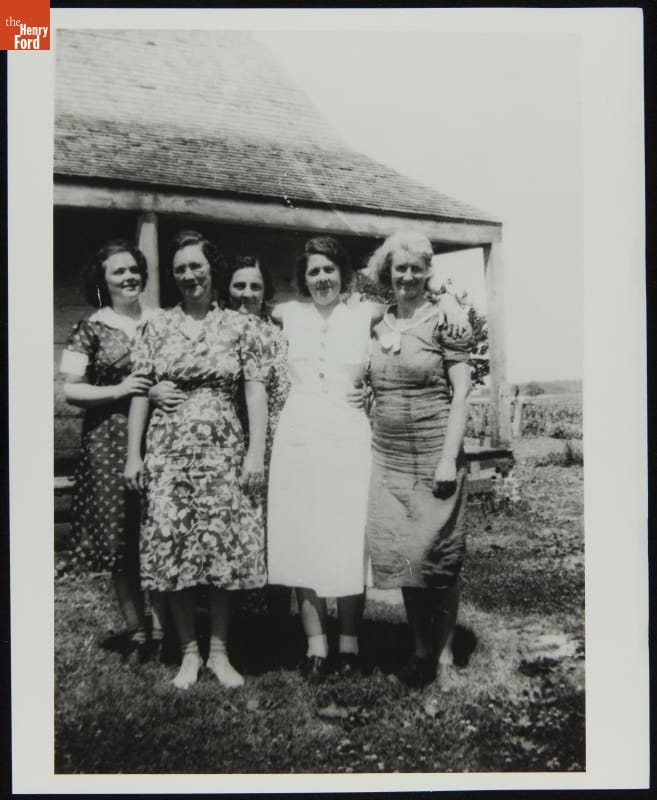 Five women posing for photo in front of a house