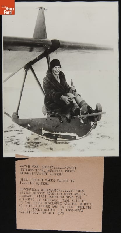 Woman sits on a thin conveyance on snow with wings extending on either side above her; typewritten text underneath photo