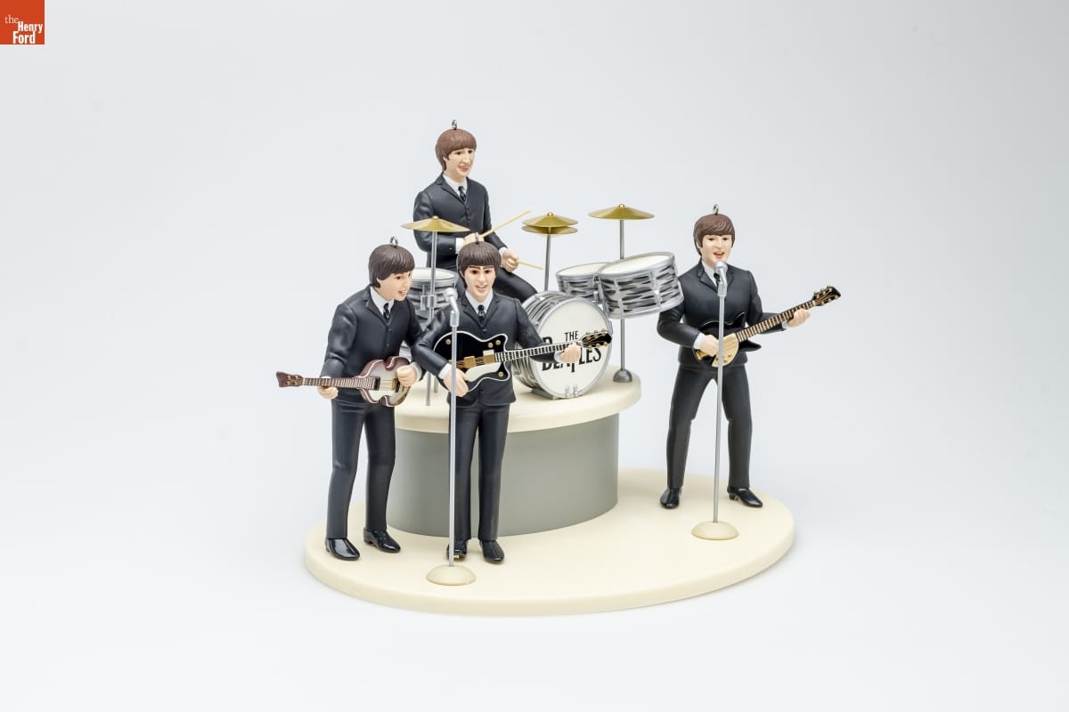 Ornament depicting four men in identical black suits, three holding guitars and one seated at a drum set