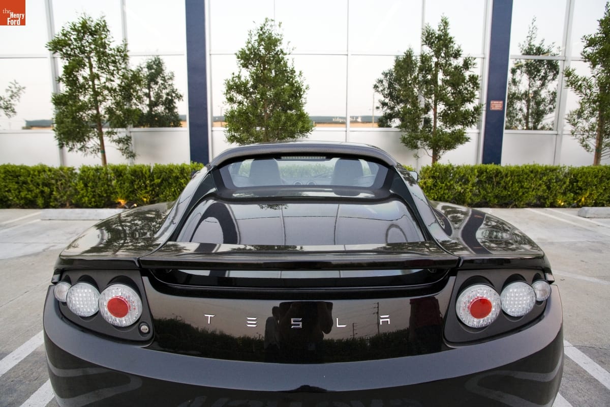Back view of low black car parked in lot by building