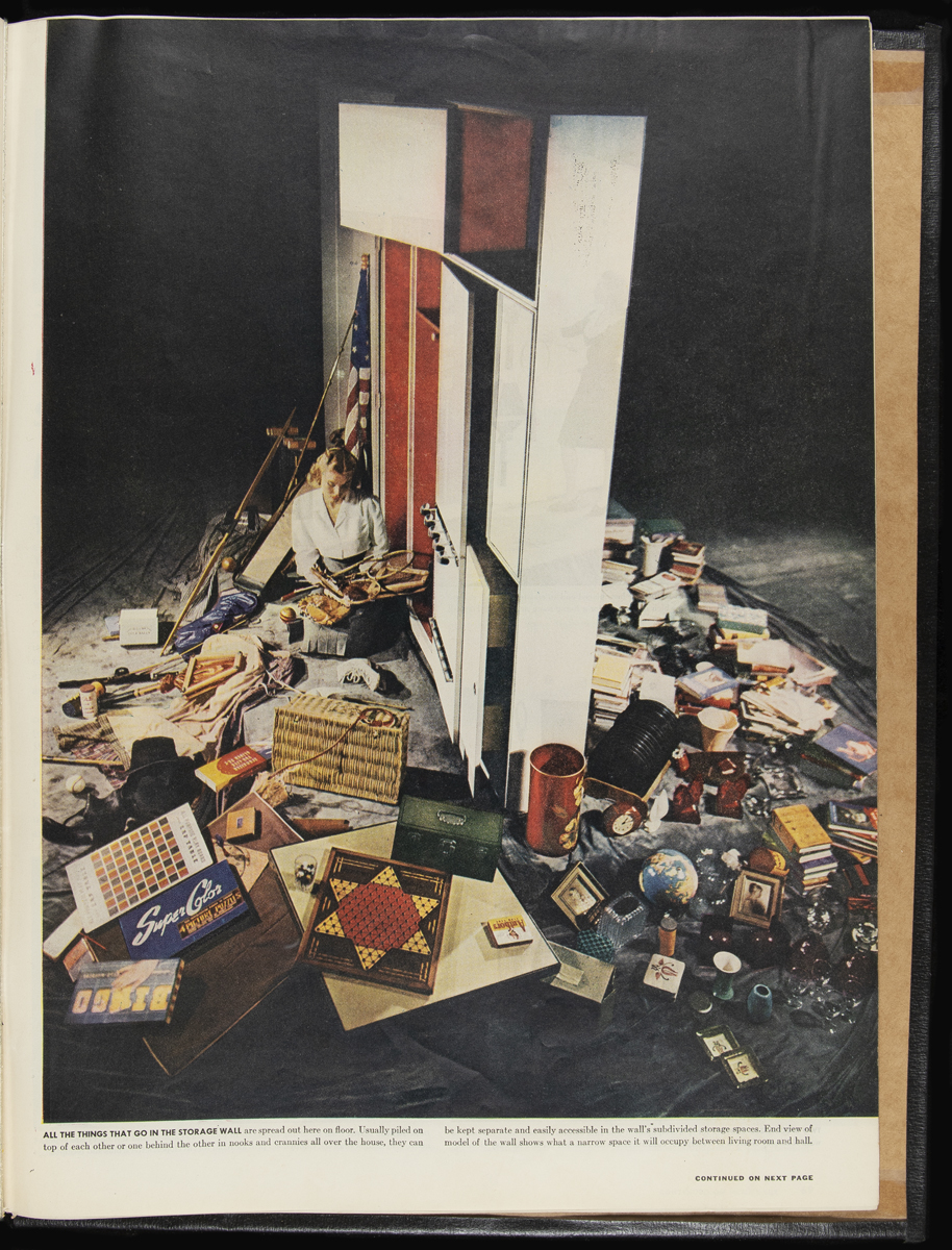 Image of woman sitting surrounded by random items next to a large, thin cabinet