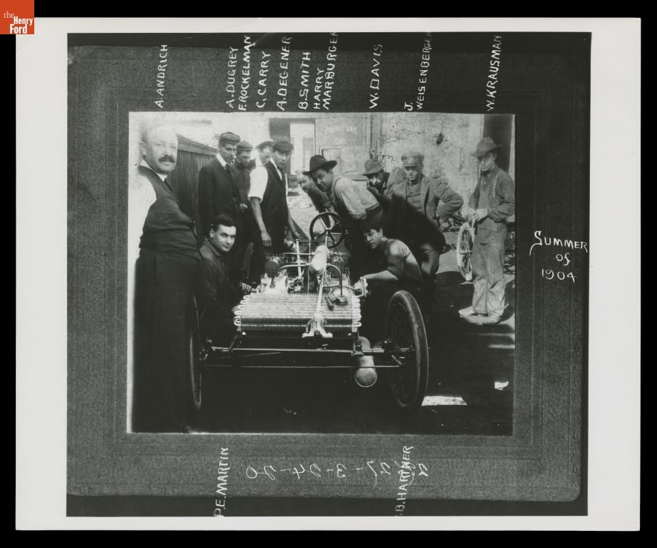 Ford Motor Company Employees with Ford Model A Racer, Summer, 1904 Matted black-and-white photo of group of men around an early open car; names written on the mat