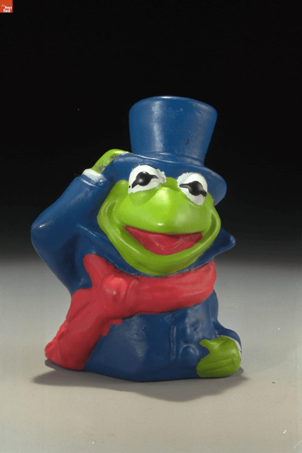 GIF cycling through toy images: frog in top hat and scarf, pig in dress and bonnet, and blue creature with hooked nose in yellow top hat and holding a book