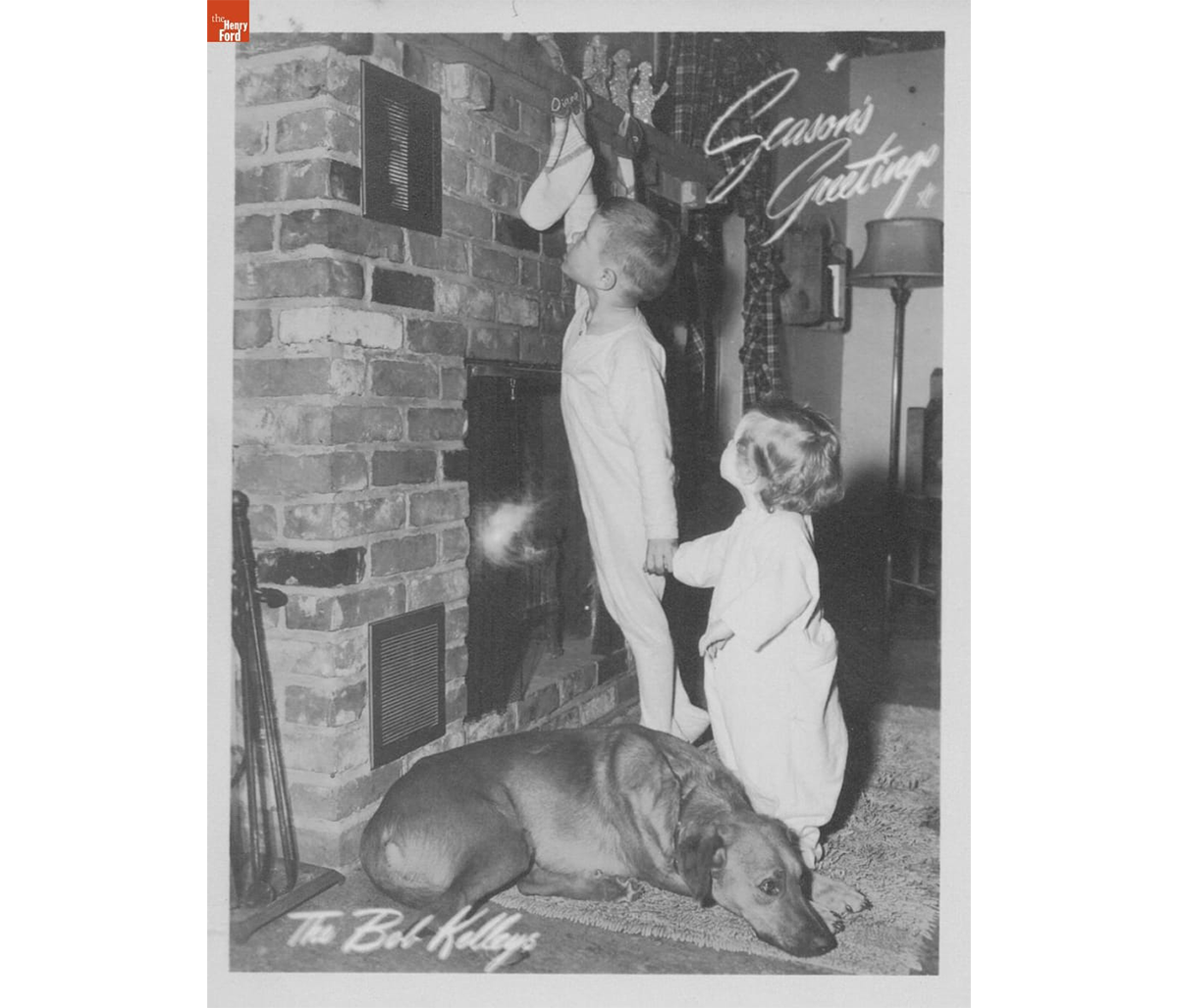 Kelley family Christmas card featuring Bobby hanging Diane's stocking on the Heatilator, December 1949. / THF723655.